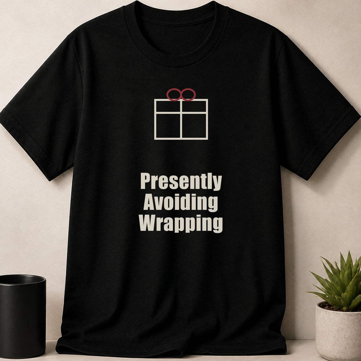 A black crewneck t-shirt featuring a gift box graphic and the text Presently Avoiding Wrapping.