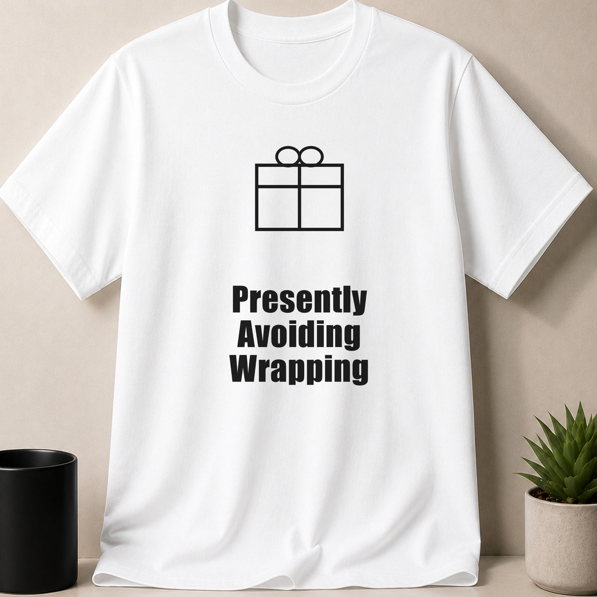 A white t-shirt featuring a black gift box graphic and the text Presently Avoiding Wrapping.