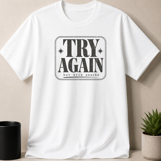 White t-shirt with distressed grey text that reads "TRY AGAIN but with snacks".