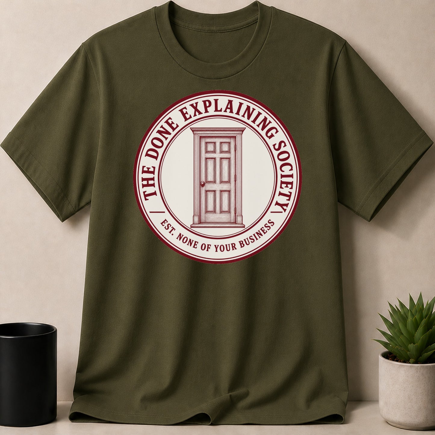 Olive t-shirt with a circular logo featuring a red door and text.