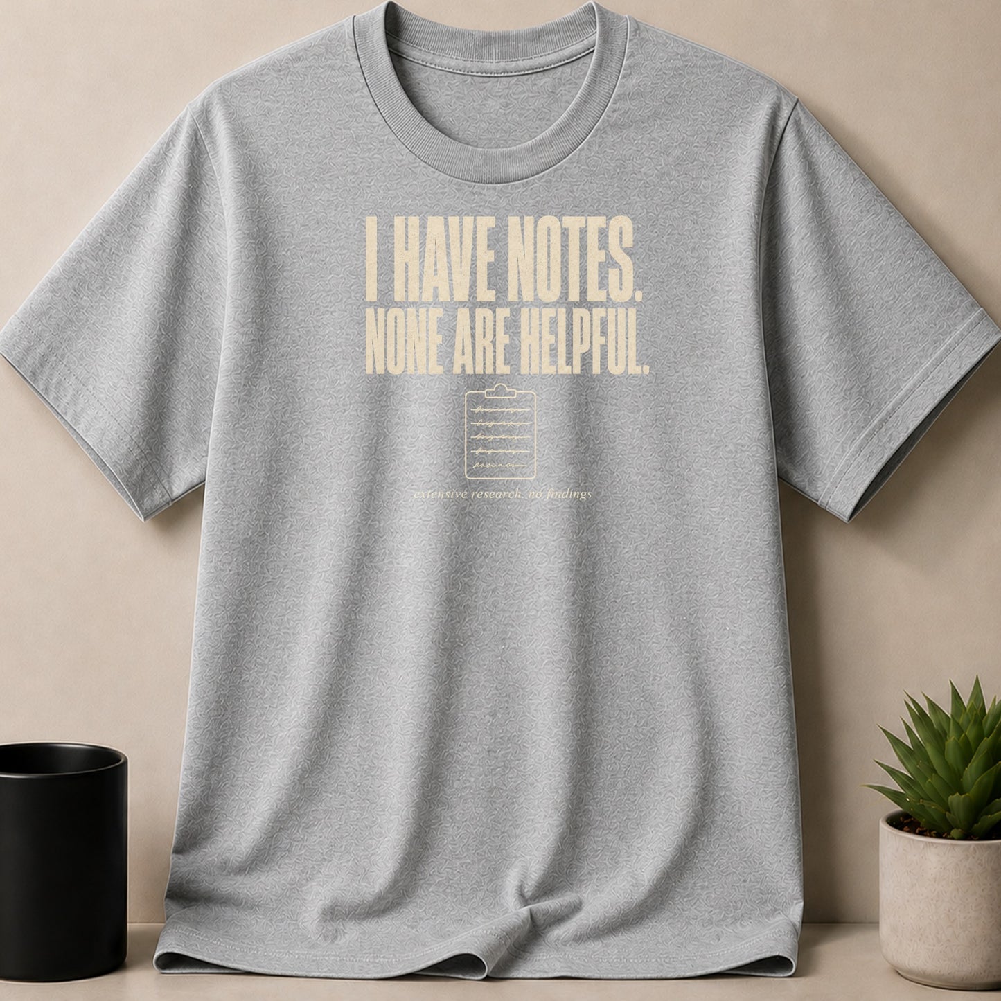 Grey t-shirt with cream text "I HAVE NOTES. NONE ARE HELPFUL." and clipboard graphic.
