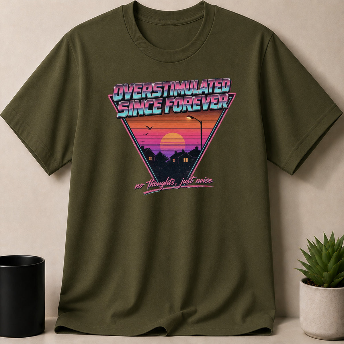 Green t-shirt with retro graphic: "Overstimulated Since Forever, No Thoughts, Just Noise."