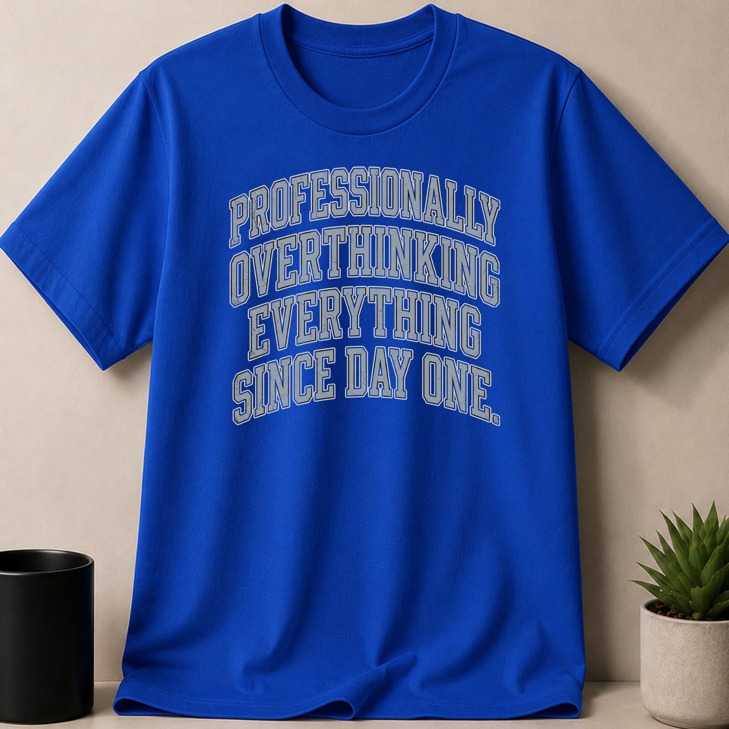 Blue t-shirt with "Professionally Overthinking Everything Since Day One" text.