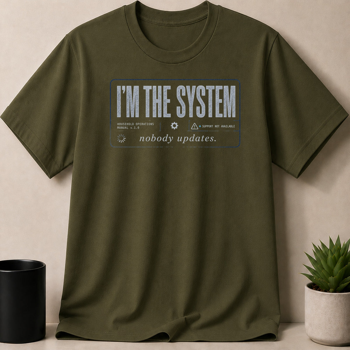 Olive green t-shirt with "I'M THE SYSTEM nobody updates." text.