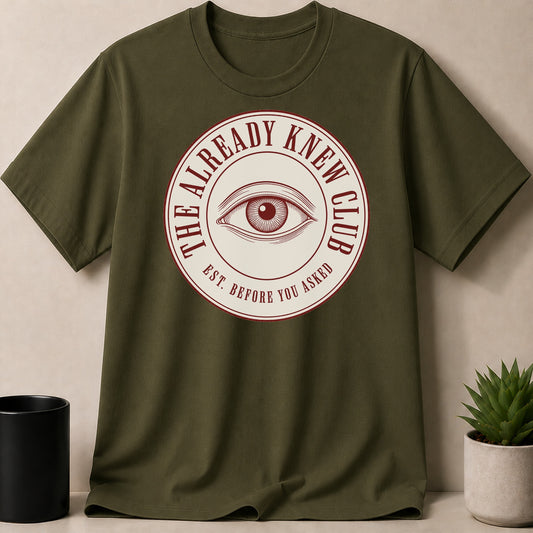 Olive green t-shirt with a circular logo featuring an eye and text.
