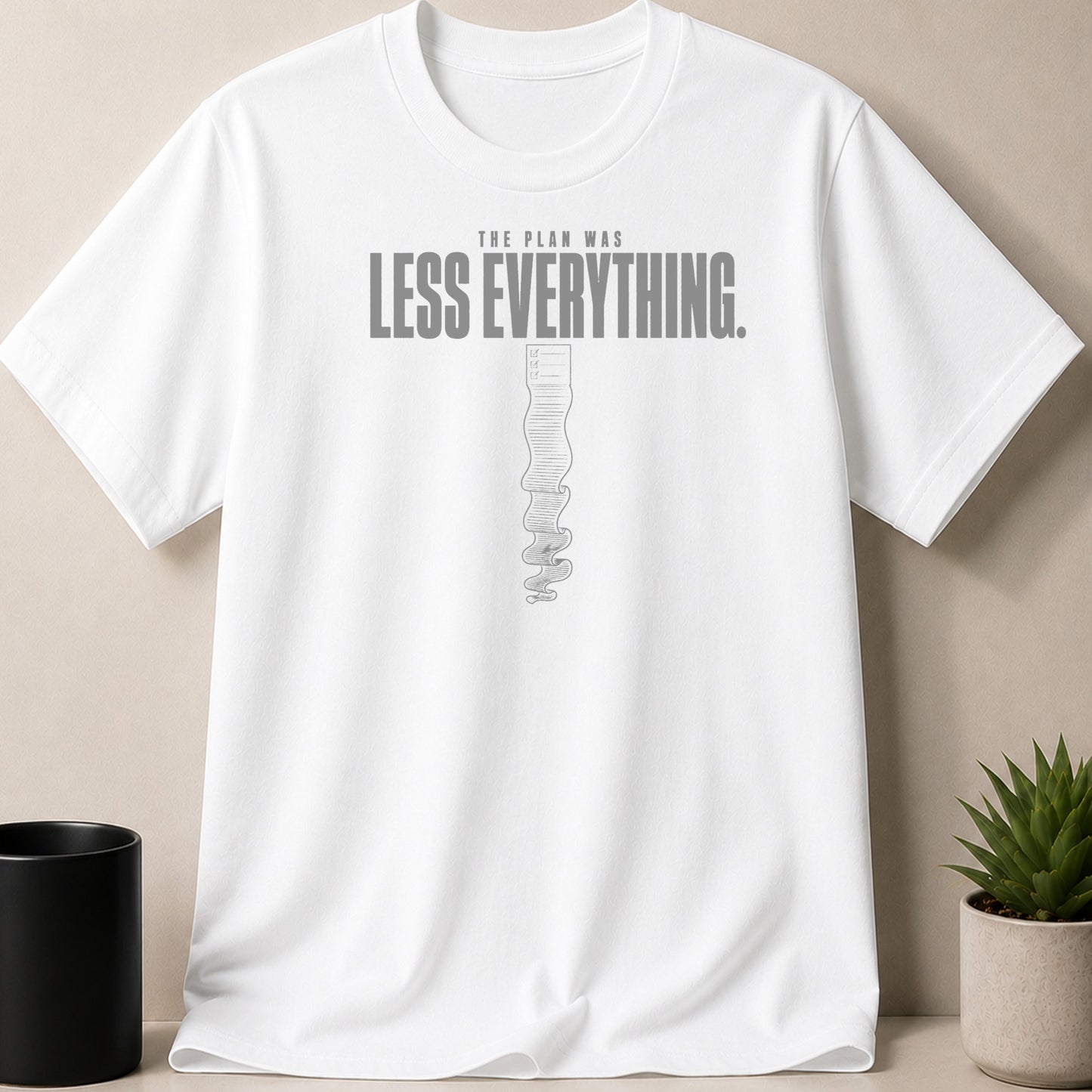 White t-shirt with gray text "THE PLAN WAS LESS EVERYTHING." and a checklist graphic.