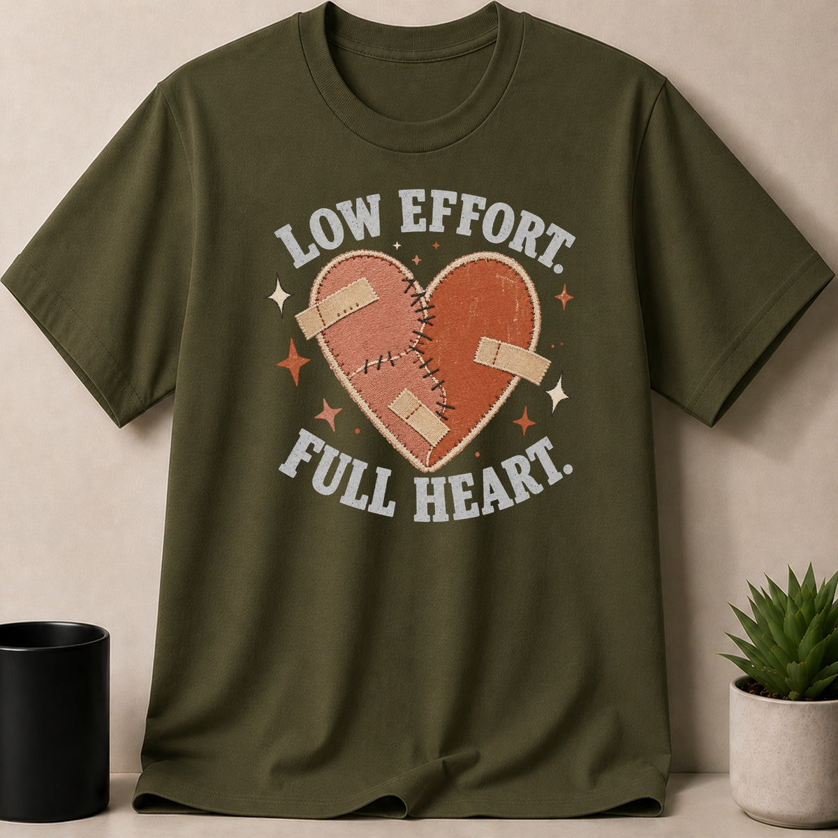 Green t-shirt with a stitched heart graphic and "Low Effort. Full Heart." text.