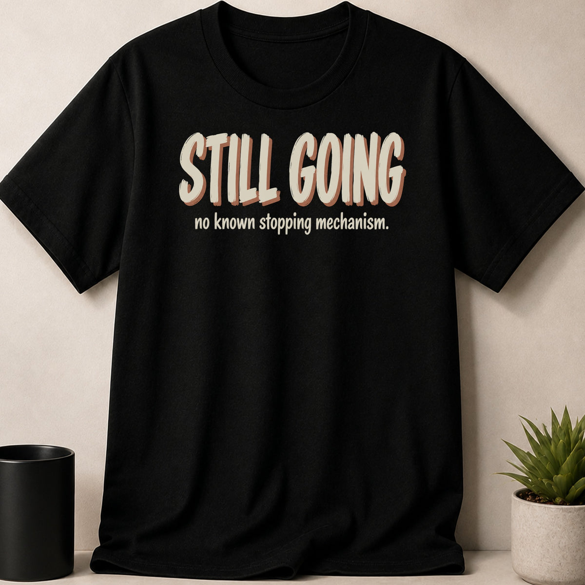 Black t-shirt with "STILL GOING" and "no known stopping mechanism" text.