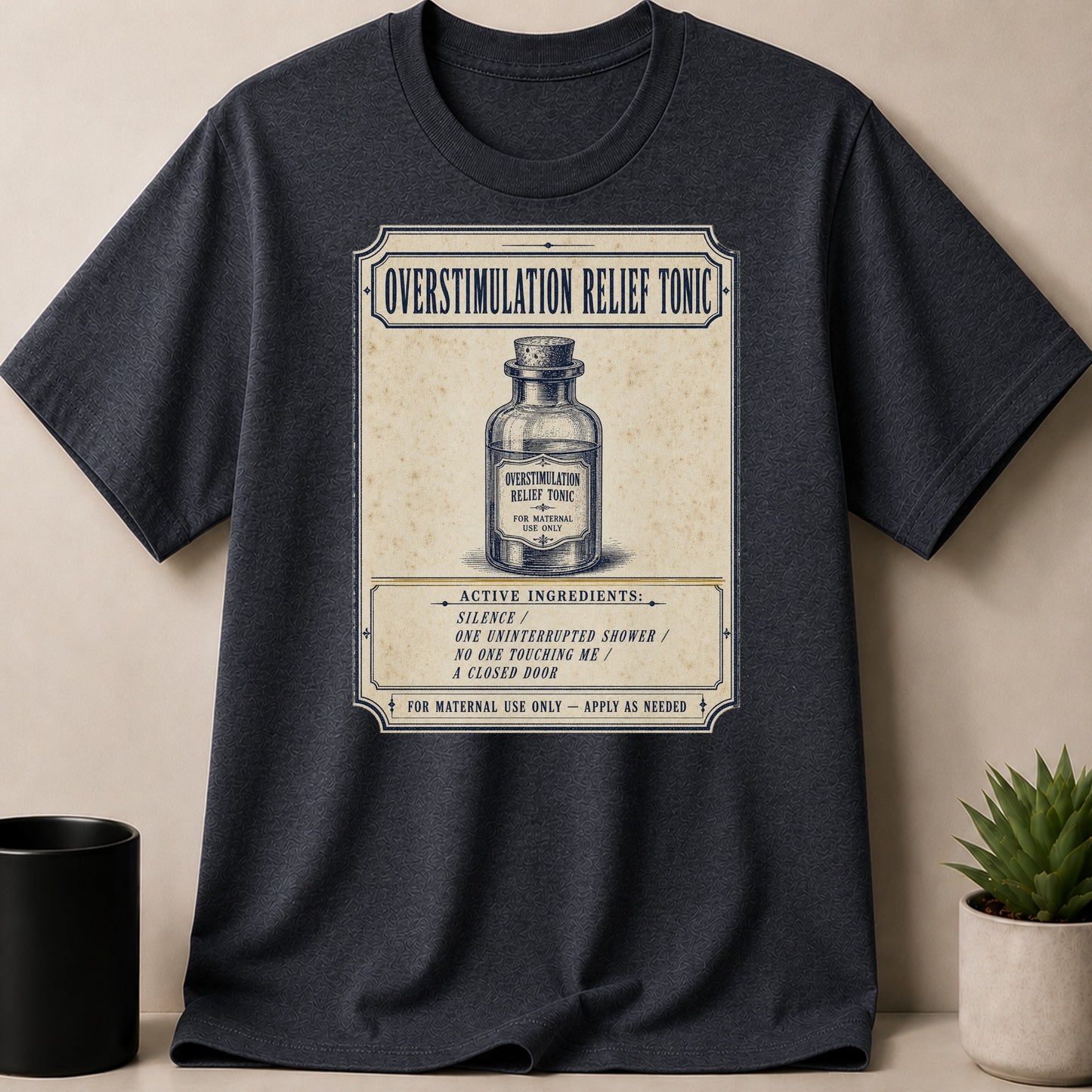 Dark heather t-shirt with label: Overstimulation Relief Tonic, Active Ingredients: Silence, Shower, No Touching, Closed Door.