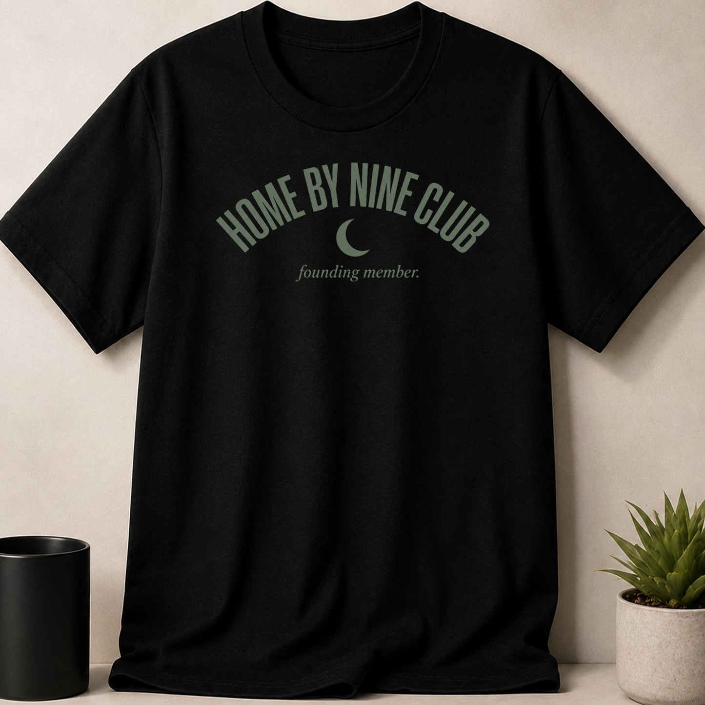 Black t-shirt with green text "HOME BY NINE CLUB founding member." and a crescent moon.