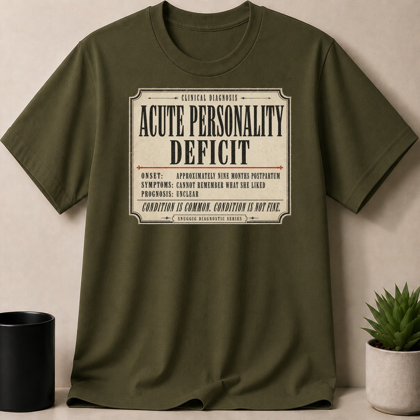 Olive green t-shirt with "Acute Personality Deficit" diagnosis print.