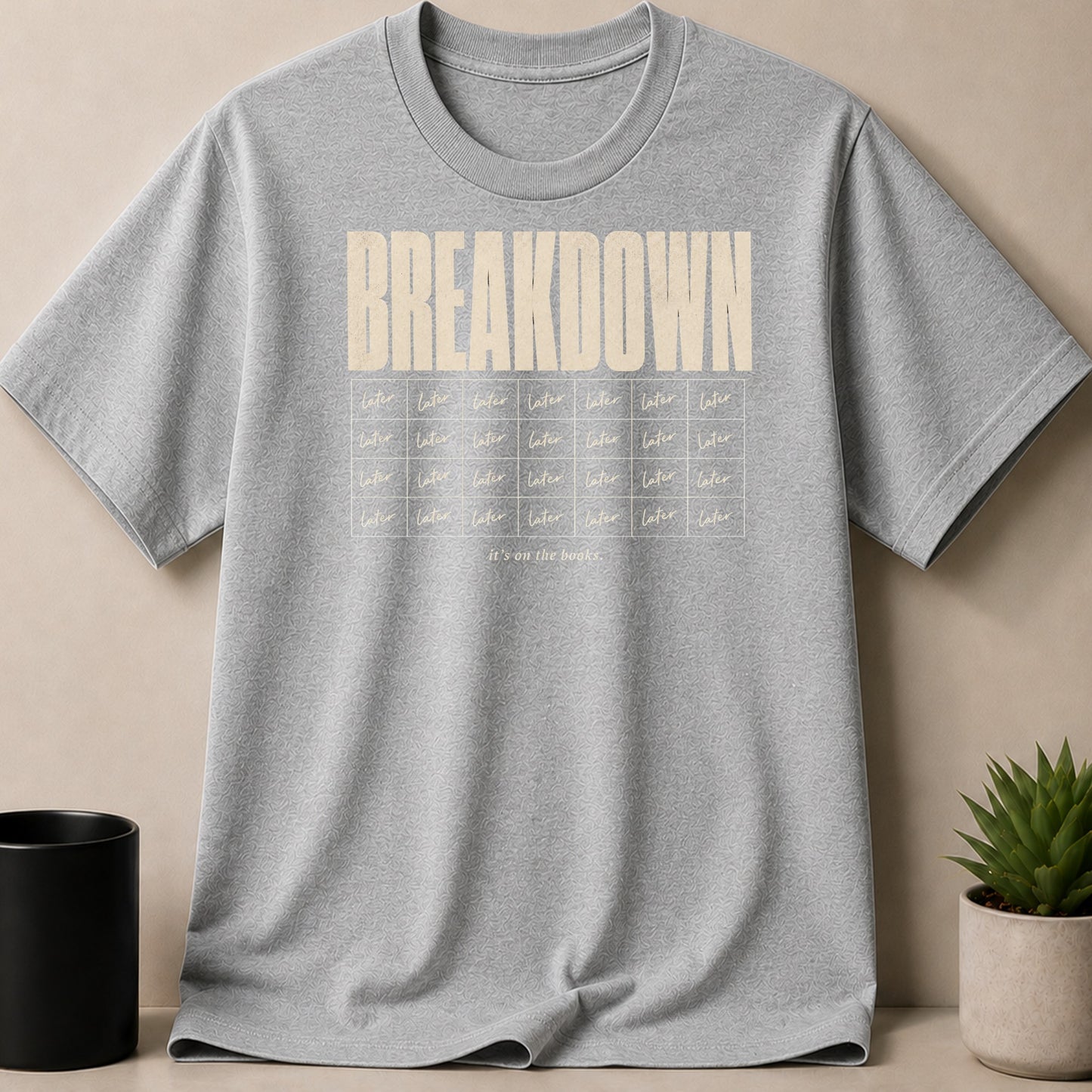 Grey t-shirt with "BREAKDOWN" and grid of "later" words and "it's on the books."