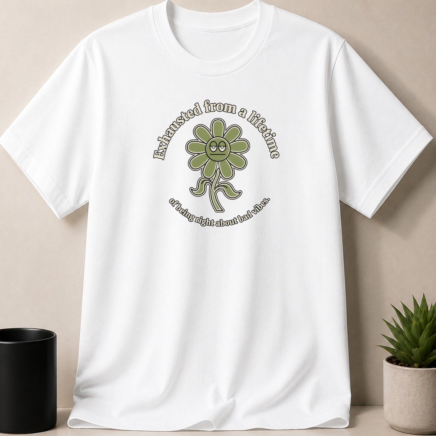 White t-shirt with a green flower graphic and text reading "Exhausted from a lifetime of being right about bad vibes."