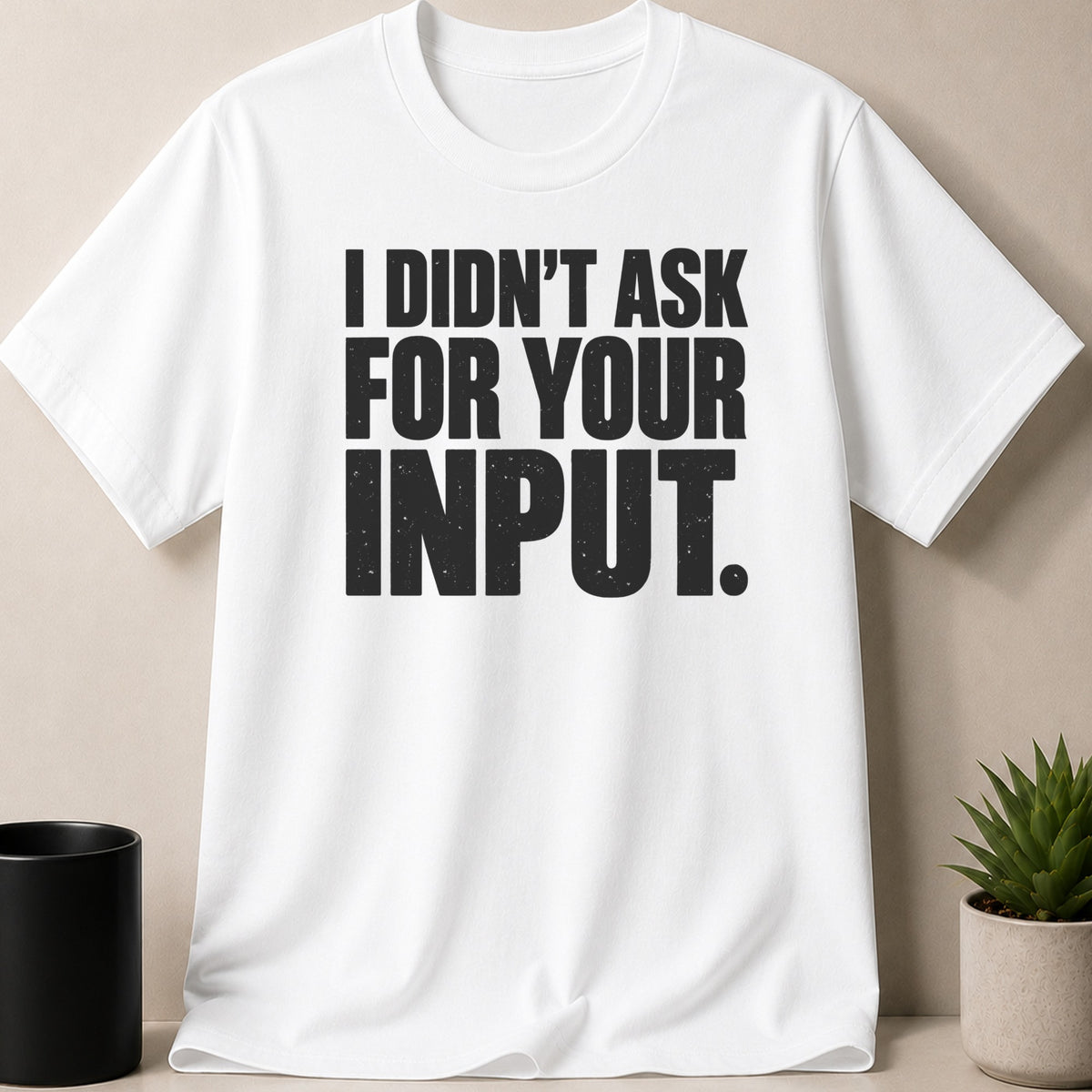 A white short-sleeved t-shirt features bold black distressed text that reads, I DIDNT ASK FOR YOUR INPUT.