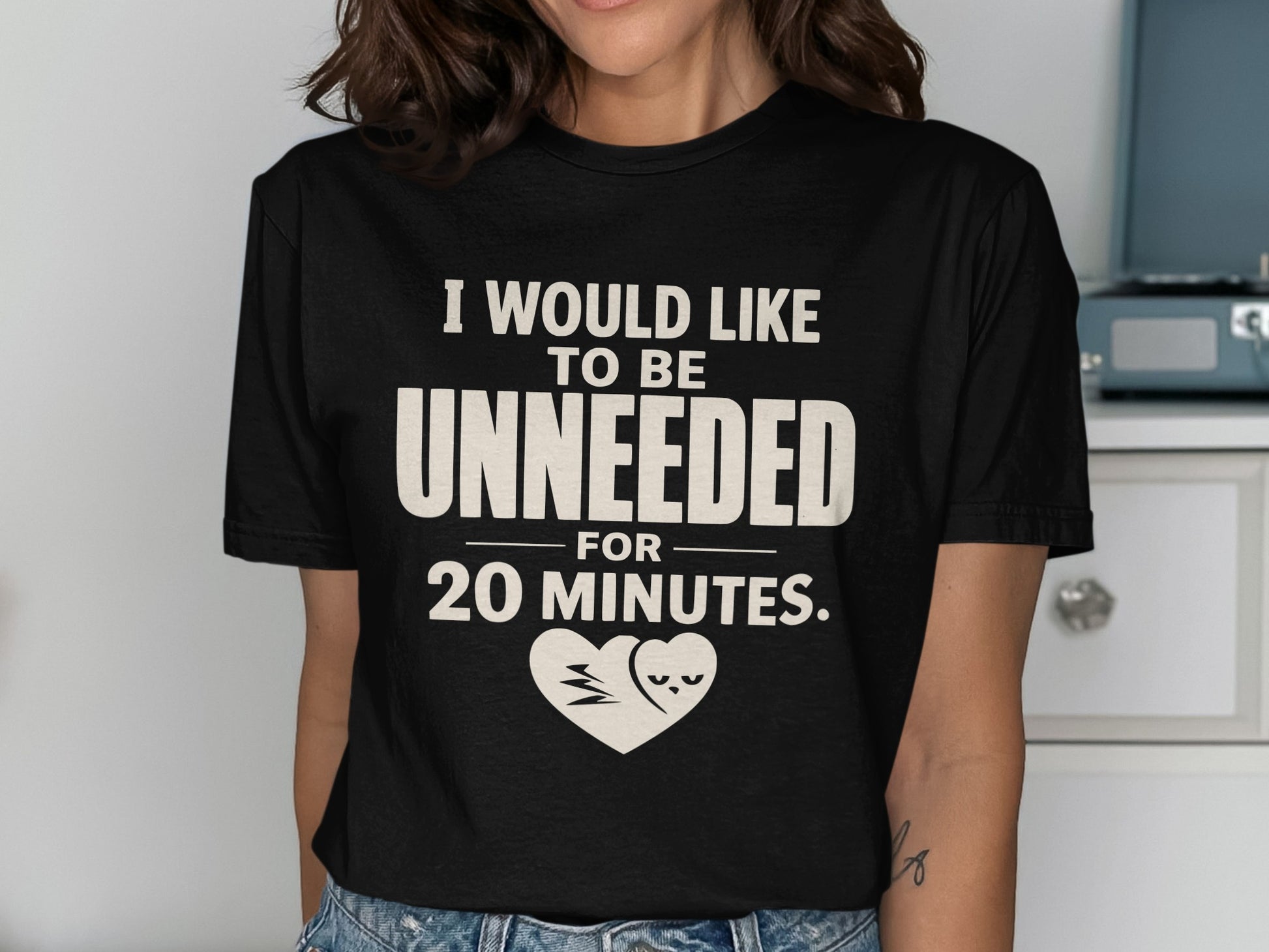 Black t-shirt with text "I WOULD LIKE TO BE UNNEEDED FOR 20 MINUTES." and heart graphic.