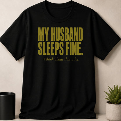 Black t-shirt with gold text "MY HUSBAND SLEEPS FINE. i think about that a lot."
