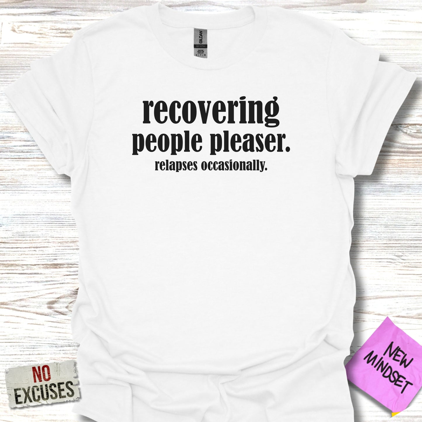 White t-shirt with black text that reads "recovering people pleaser. relapses occasionally."