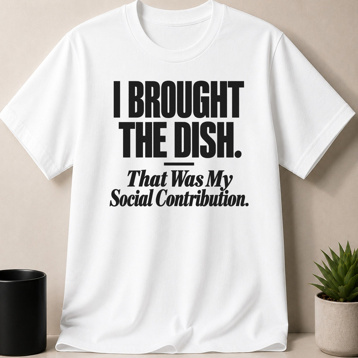 A white t-shirt printed with the black text I BROUGHT THE DISH. That Was My Social Contribution.