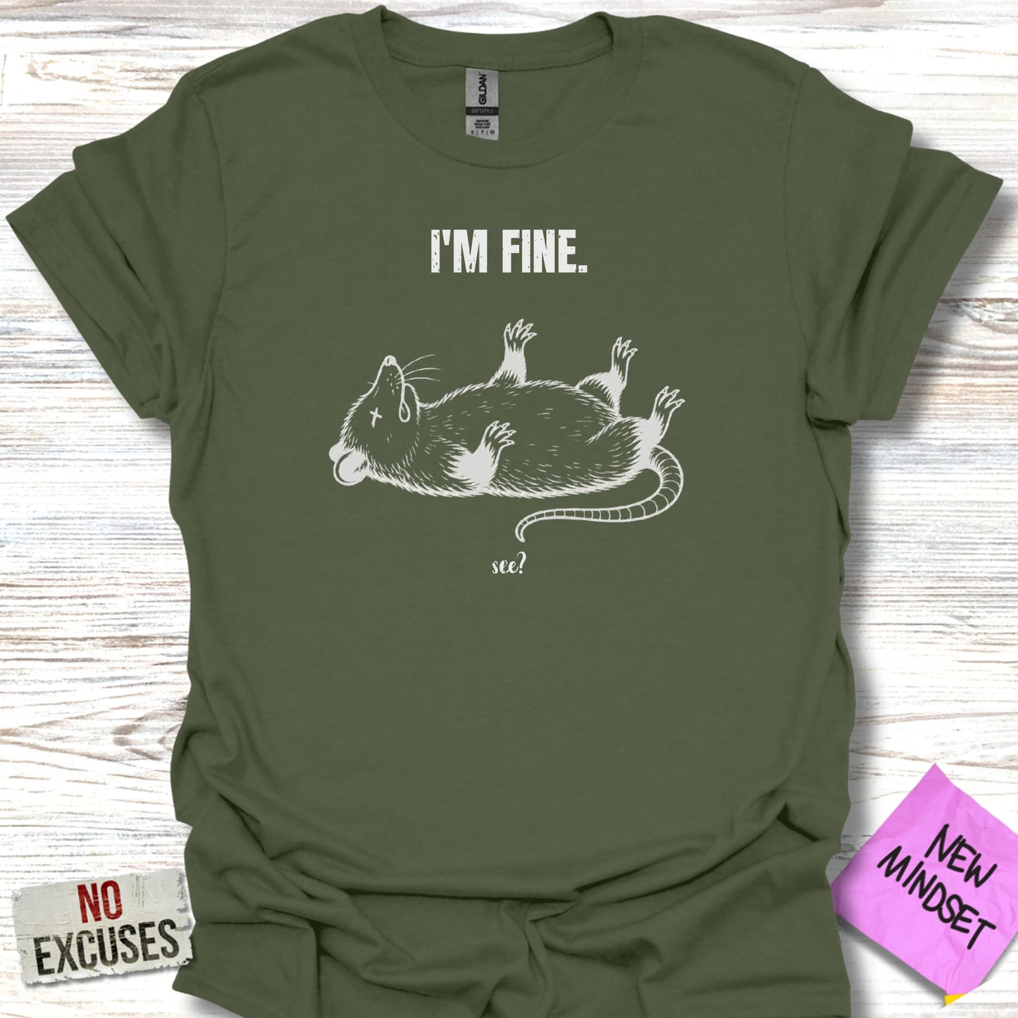 Green t-shirt with a white illustration of a rat on its back, text "I'M FINE." and "see?".