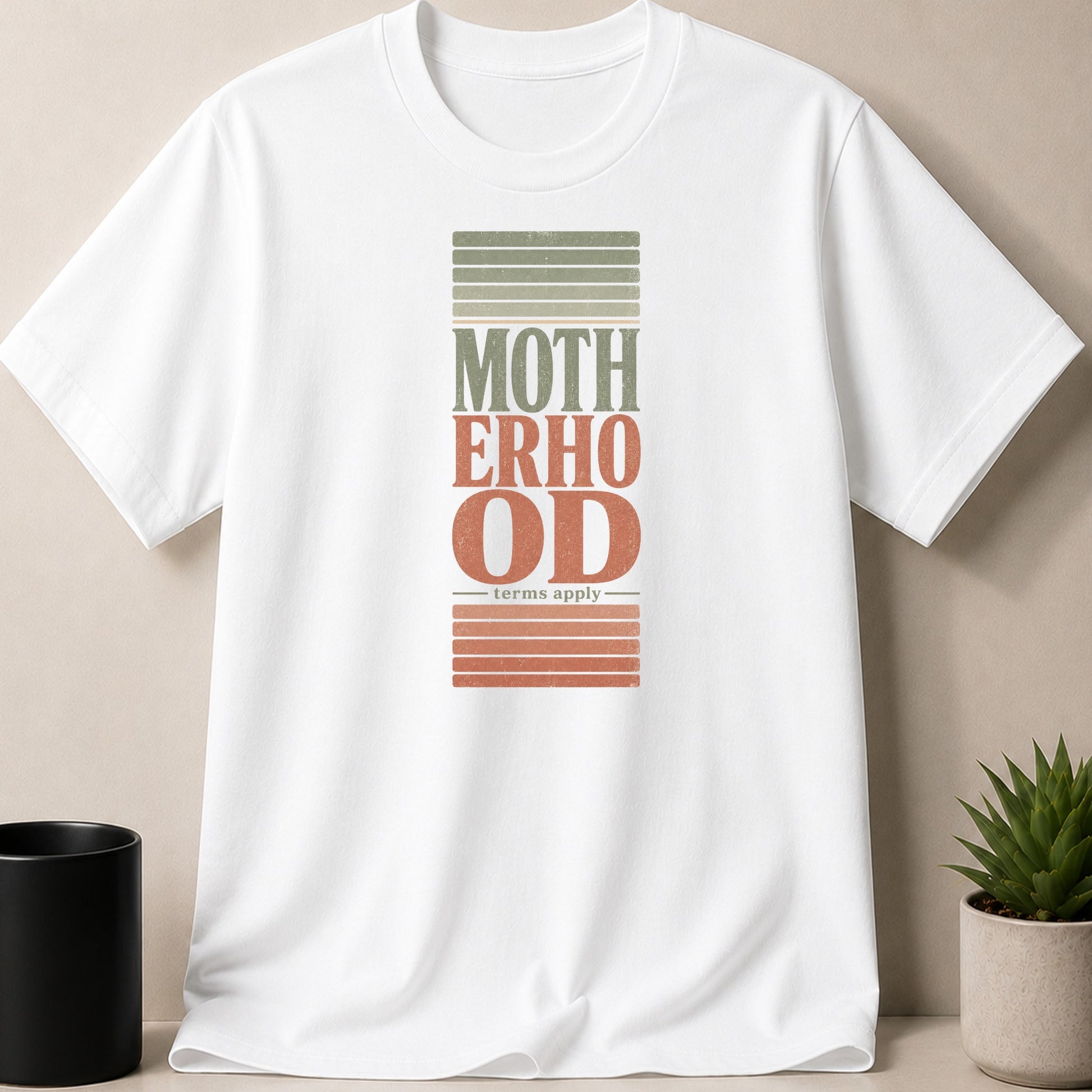 White t-shirt with "MOTHERHOOD - terms apply -" graphic in distressed retro style.