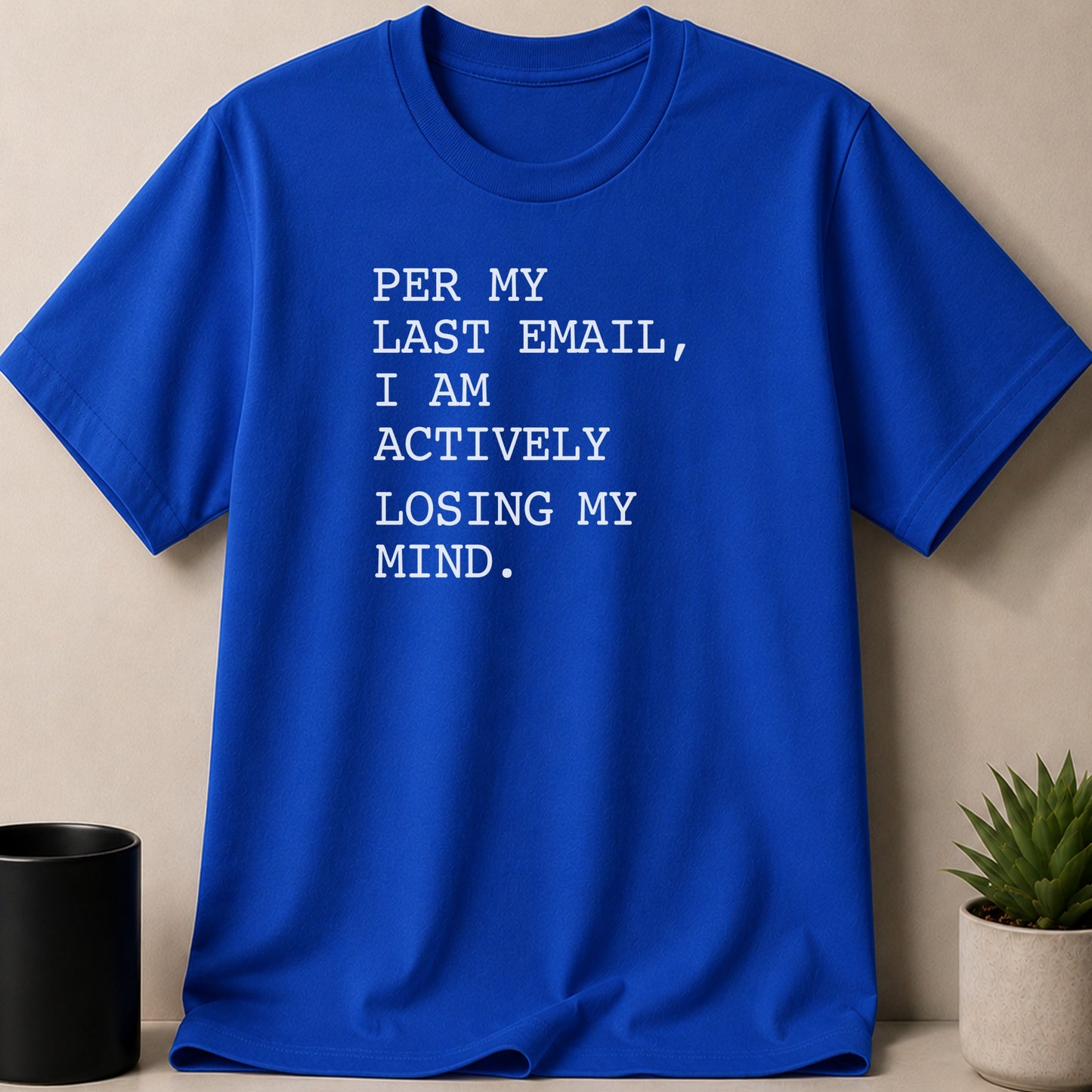 Blue t-shirt with white text that reads "PER MY LAST EMAIL, I AM ACTIVELY LOSING MY MIND."
