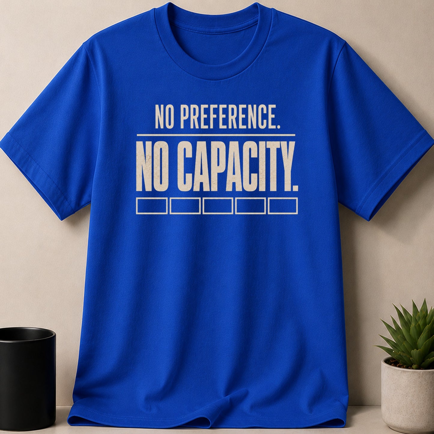 Blue t-shirt with white text "NO PREFERENCE. NO CAPACITY." and empty boxes.