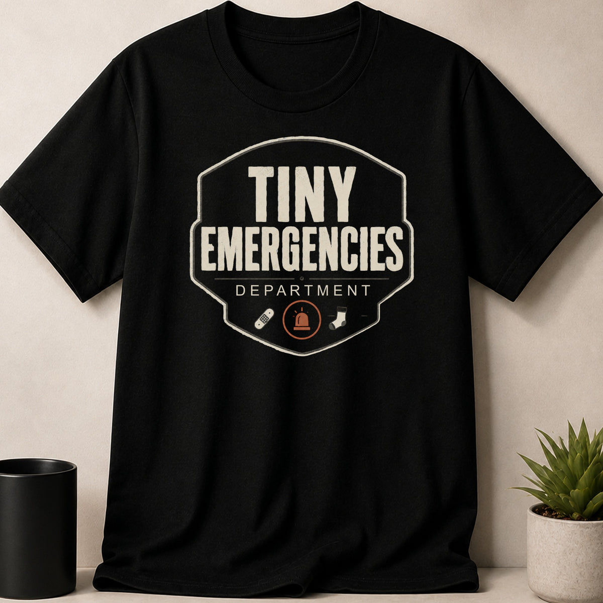 Black t-shirt with "Tiny Emergencies Department" text and playful icons.