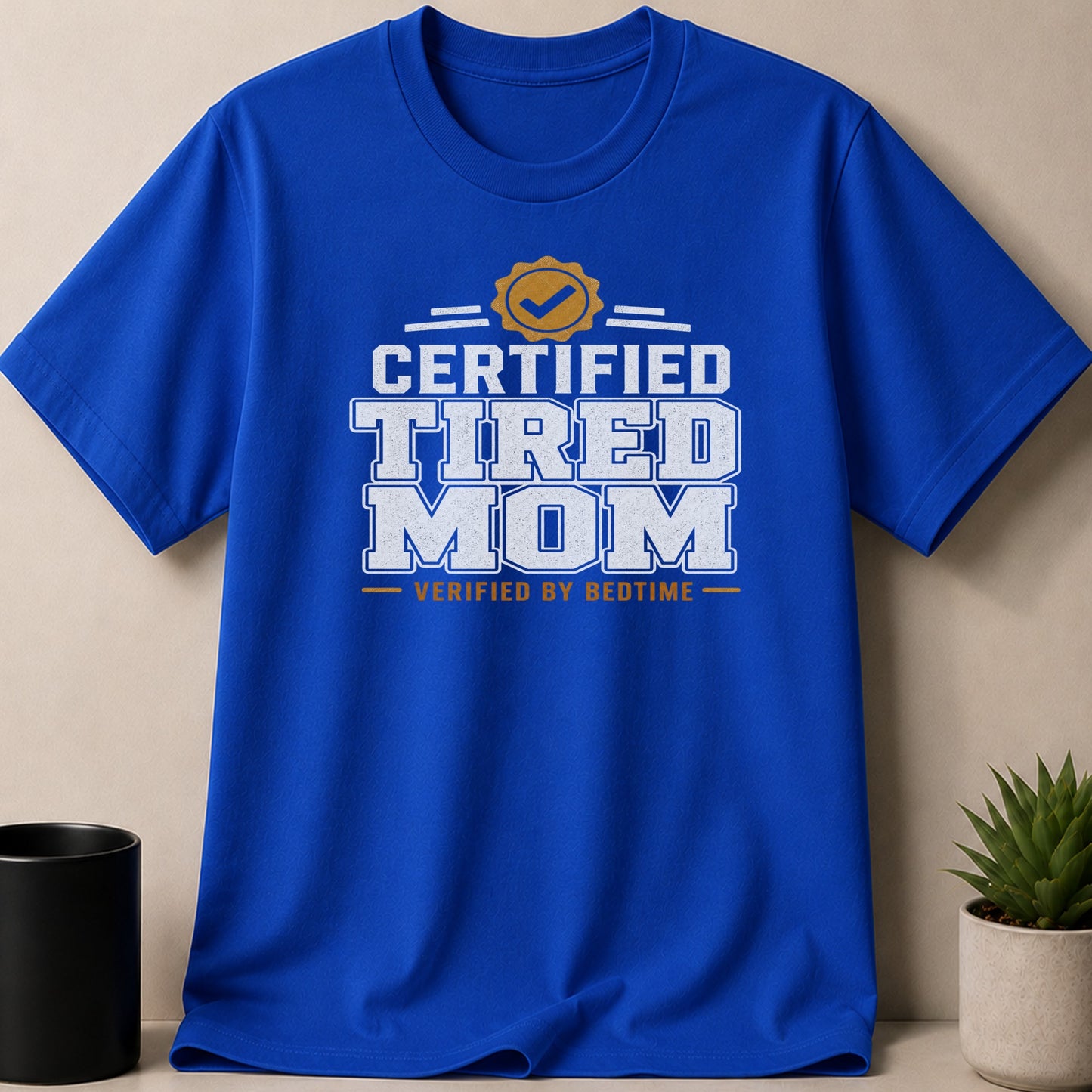 Blue t-shirt with "Certified Tired Mom Verified by Bedtime" text.