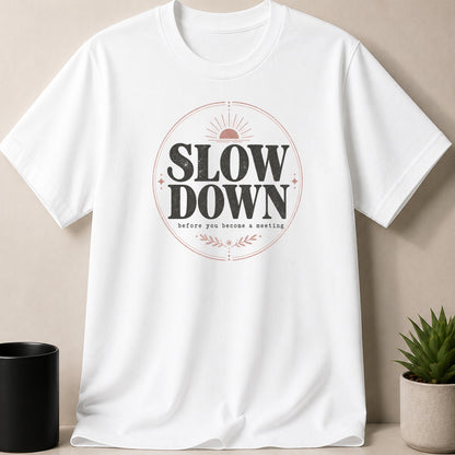 White t-shirt with "SLOW DOWN before you become a meeting" text and sun graphic.