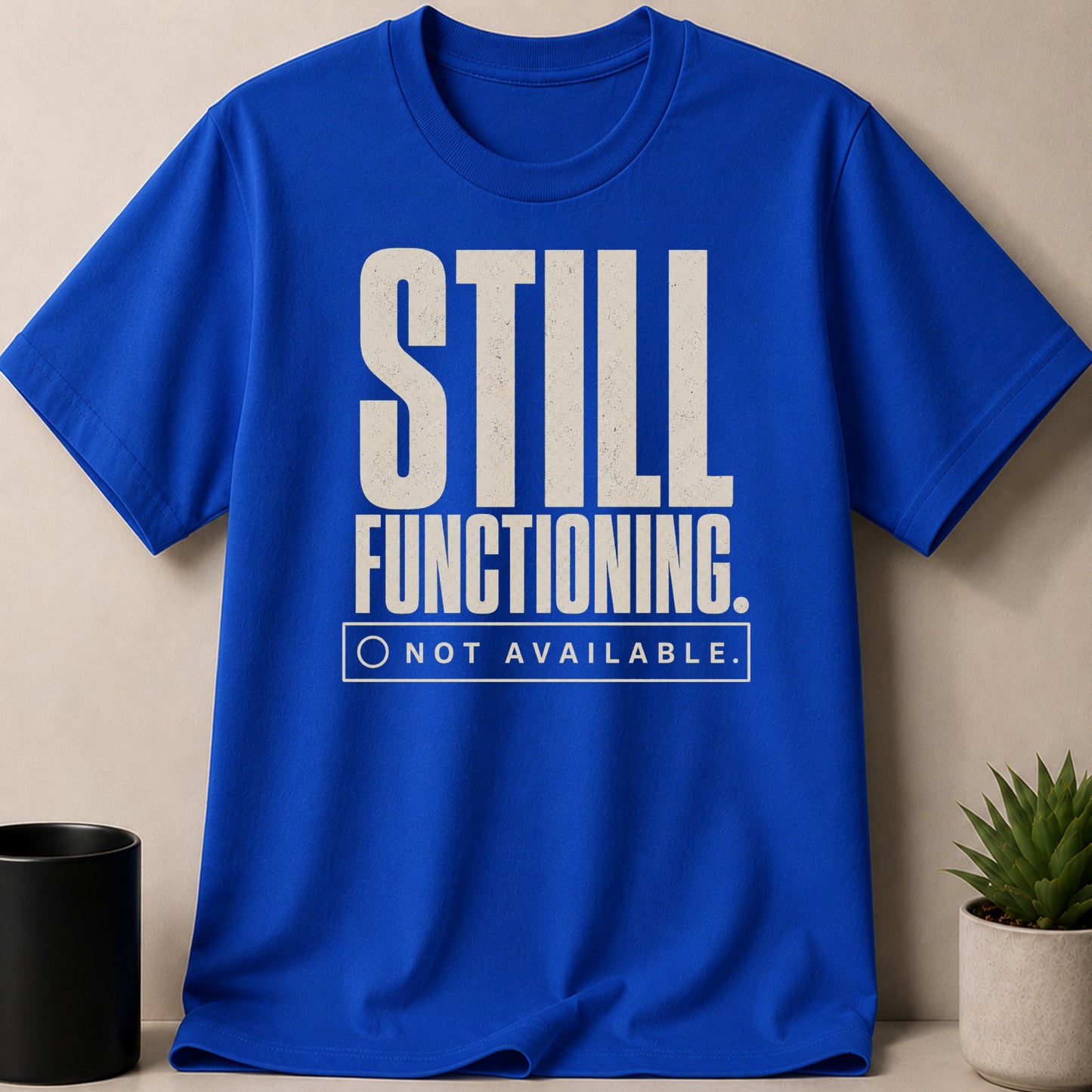 Blue t-shirt with "STILL FUNCTIONING. NOT AVAILABLE." text.