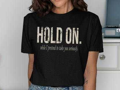 Black t-shirt with off-white text that says "HOLD ON. while I pretend to take you seriously."