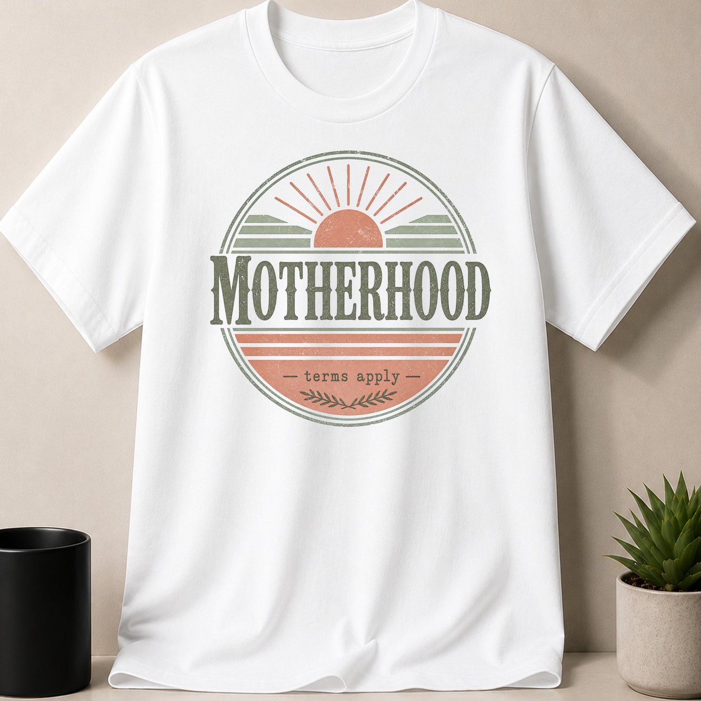 White t-shirt with central circular graphic that reads "MOTHERHOOD - terms apply".