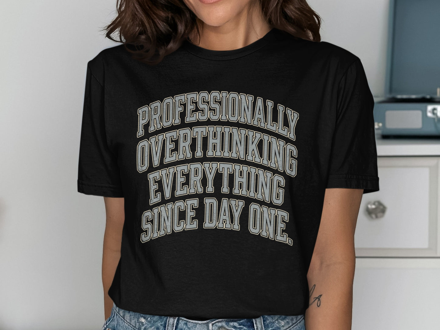 Black t-shirt with text "Professionally Overthinking Everything Since Day One"