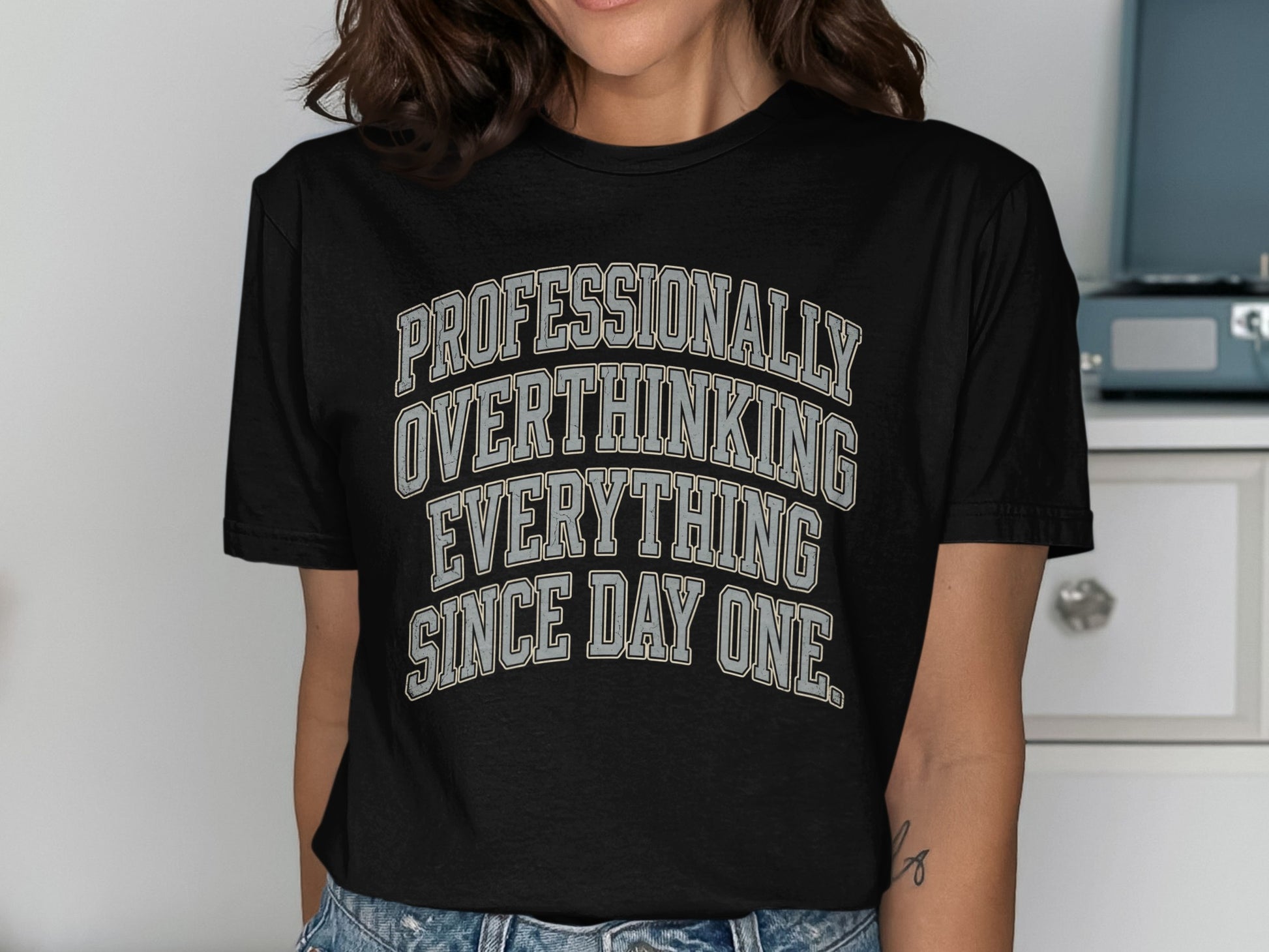 Black t-shirt with text "Professionally Overthinking Everything Since Day One"