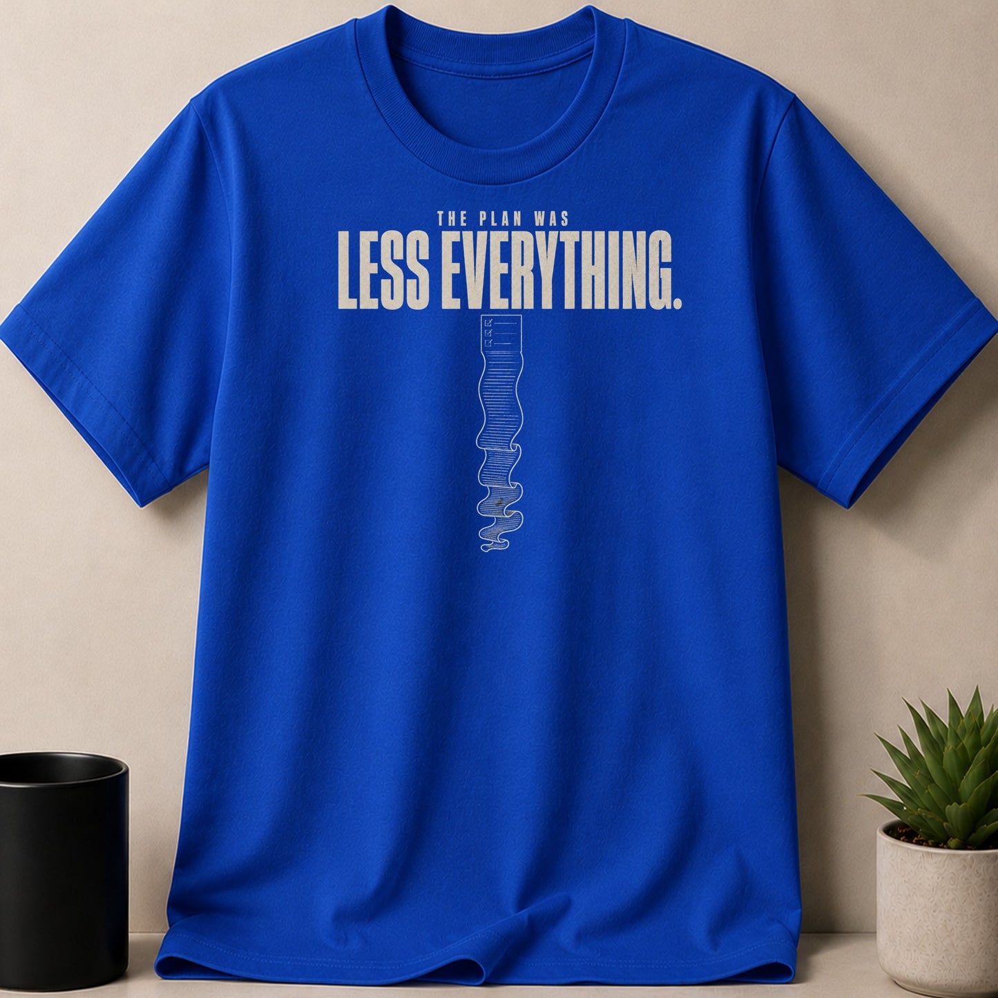 Blue t-shirt with text "THE PLAN WAS LESS EVERYTHING." and a checklist.