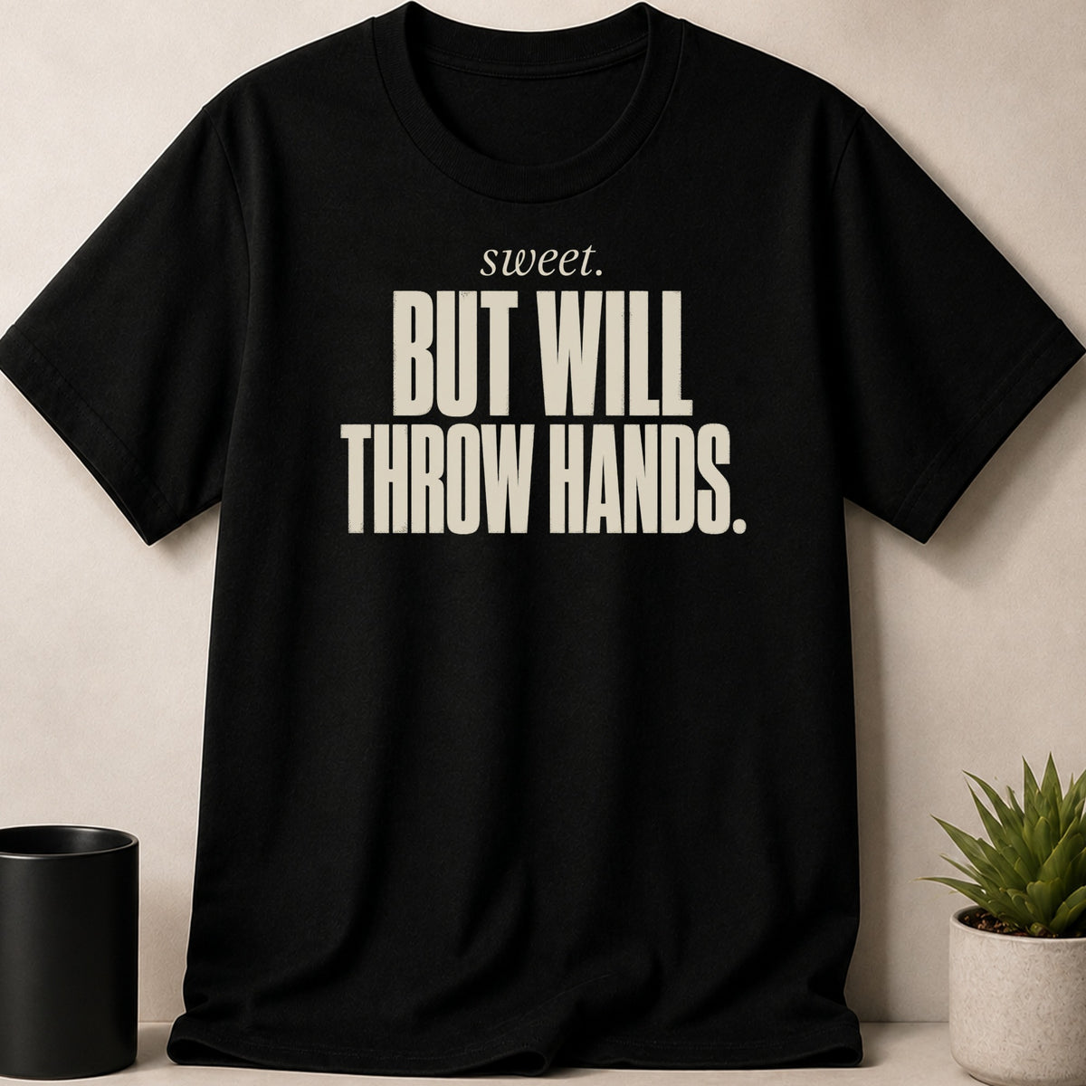 Black t-shirt with the words "sweet. BUT WILL THROW HANDS." in cream text.