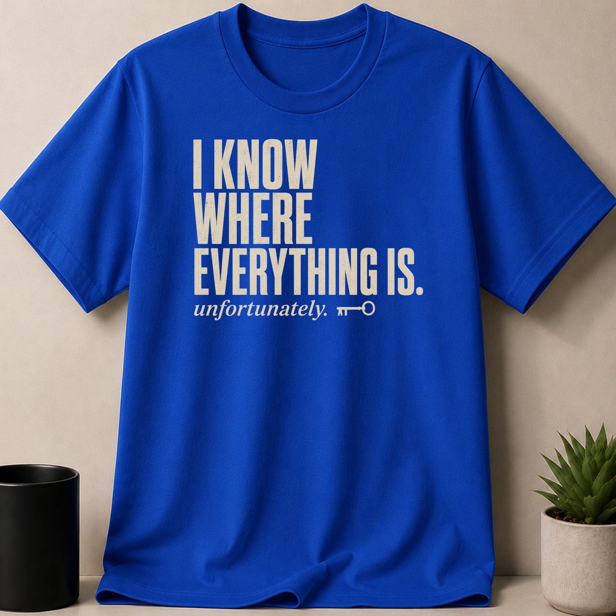 Royal blue t-shirt with cream text that reads "I KNOW WHERE EVERYTHING IS. unfortunately." and a key symbol.