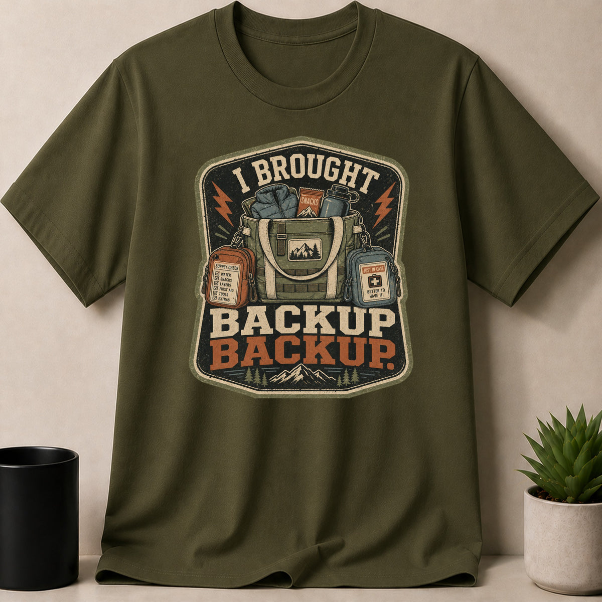 Green t-shirt with "I BROUGHT BACKUP BACKUP" graphic featuring a backpack and supplies.