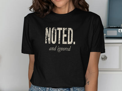 Black t-shirt with distressed "NOTED. and ignored" text in cream.