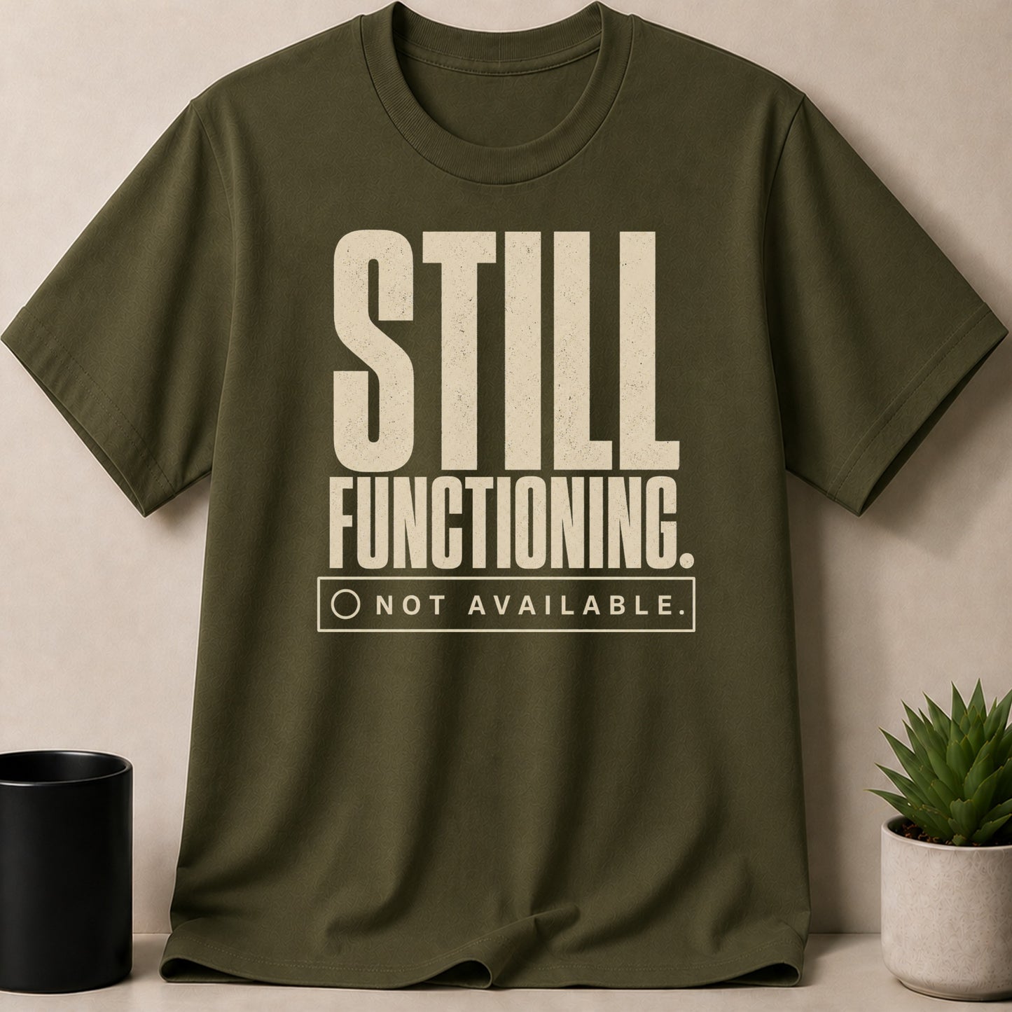 Olive green t-shirt with "STILL FUNCTIONING. NOT AVAILABLE." text and a checkbox.
