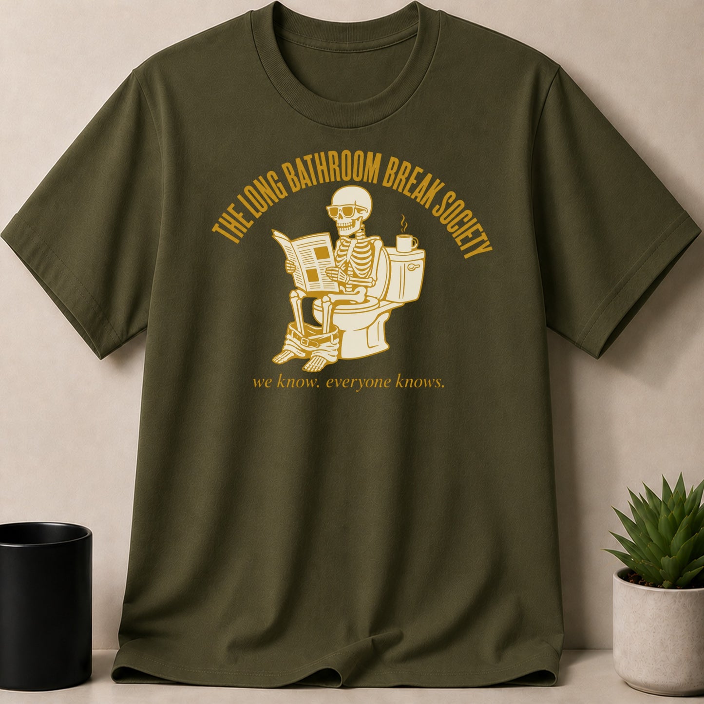 Olive t-shirt with a skeleton reading newspaper on toilet, "The Long Bathroom Break Society" text.