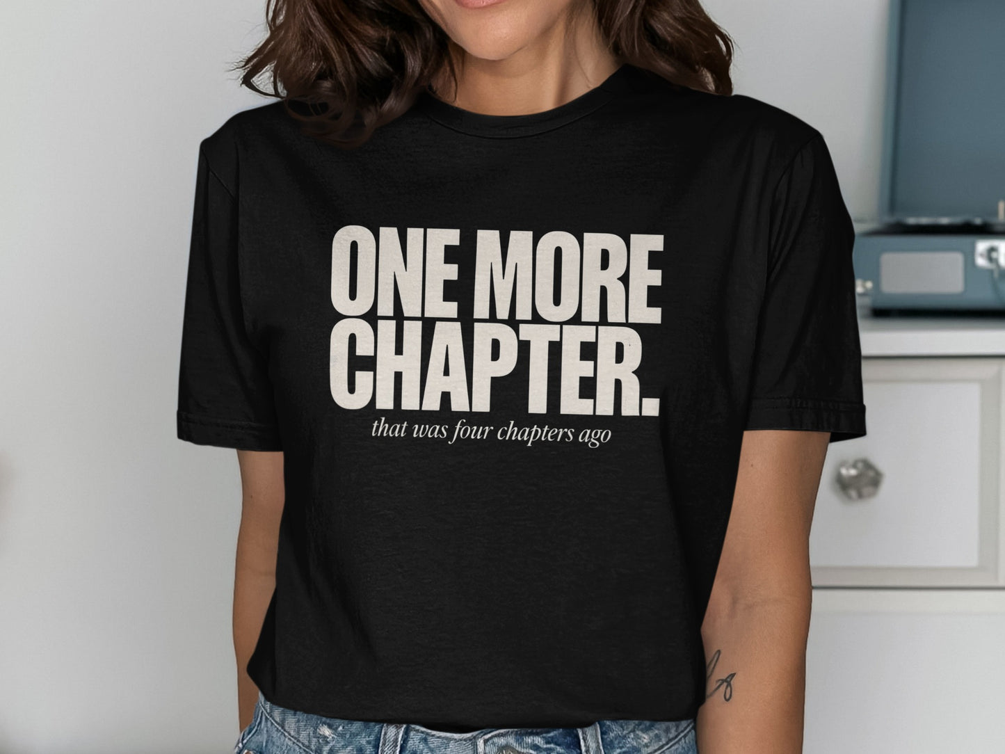 Black t-shirt with "ONE MORE CHAPTER. that was four chapters ago" text