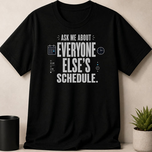 Black t-shirt with "Ask Me About Everyone Else's Schedule" slogan and calendar/clock graphics.