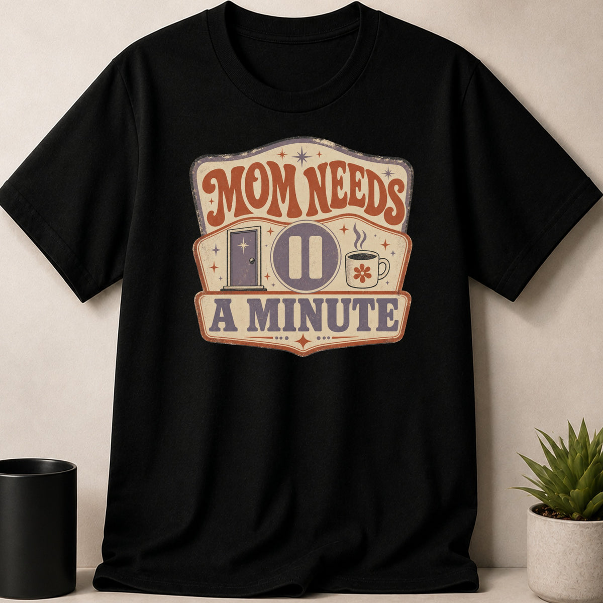 Black t-shirt with "Mom Needs A Minute" vintage graphic including a pause button and coffee cup.