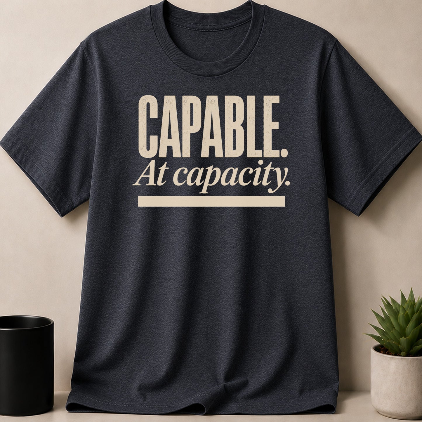 Dark t-shirt with "CAPABLE. At capacity." text printed in beige.