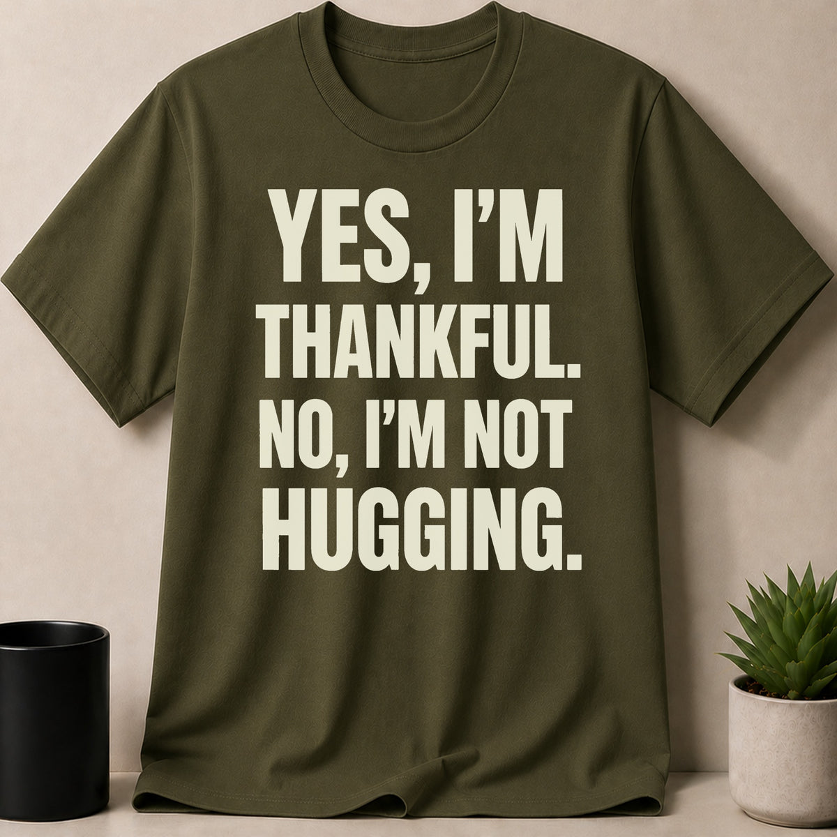 Olive green t-shirt with text: "YES, I'M THANKFUL. NO, I'M NOT HUGGING."