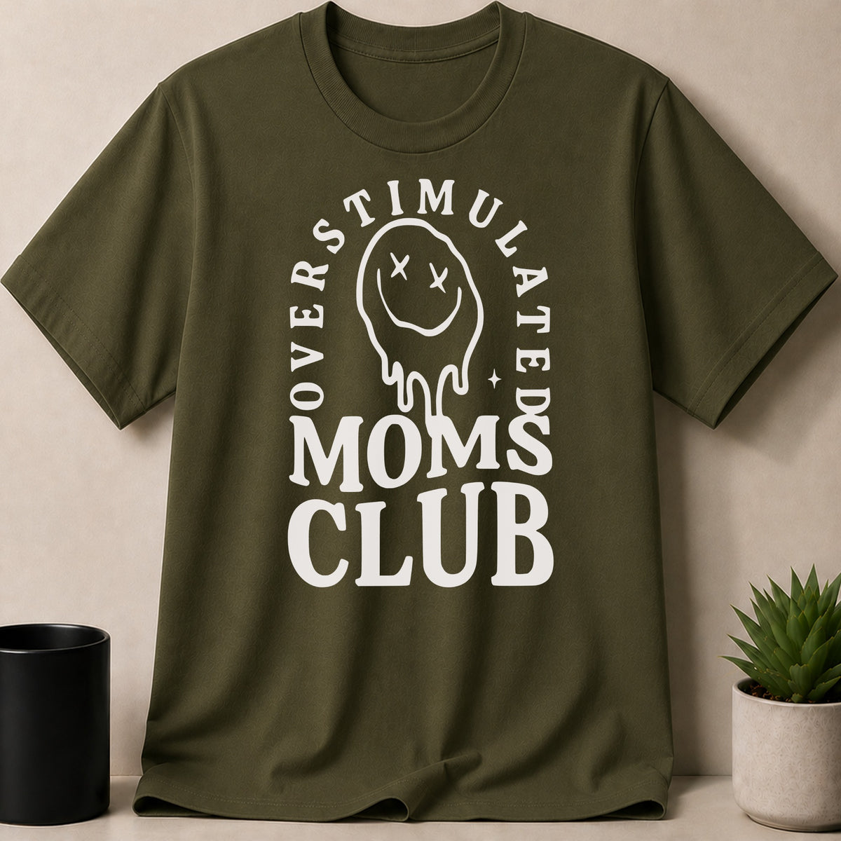 Olive green t-shirt with "Overstimulated Moms Club" text and dripping smiley face graphic.