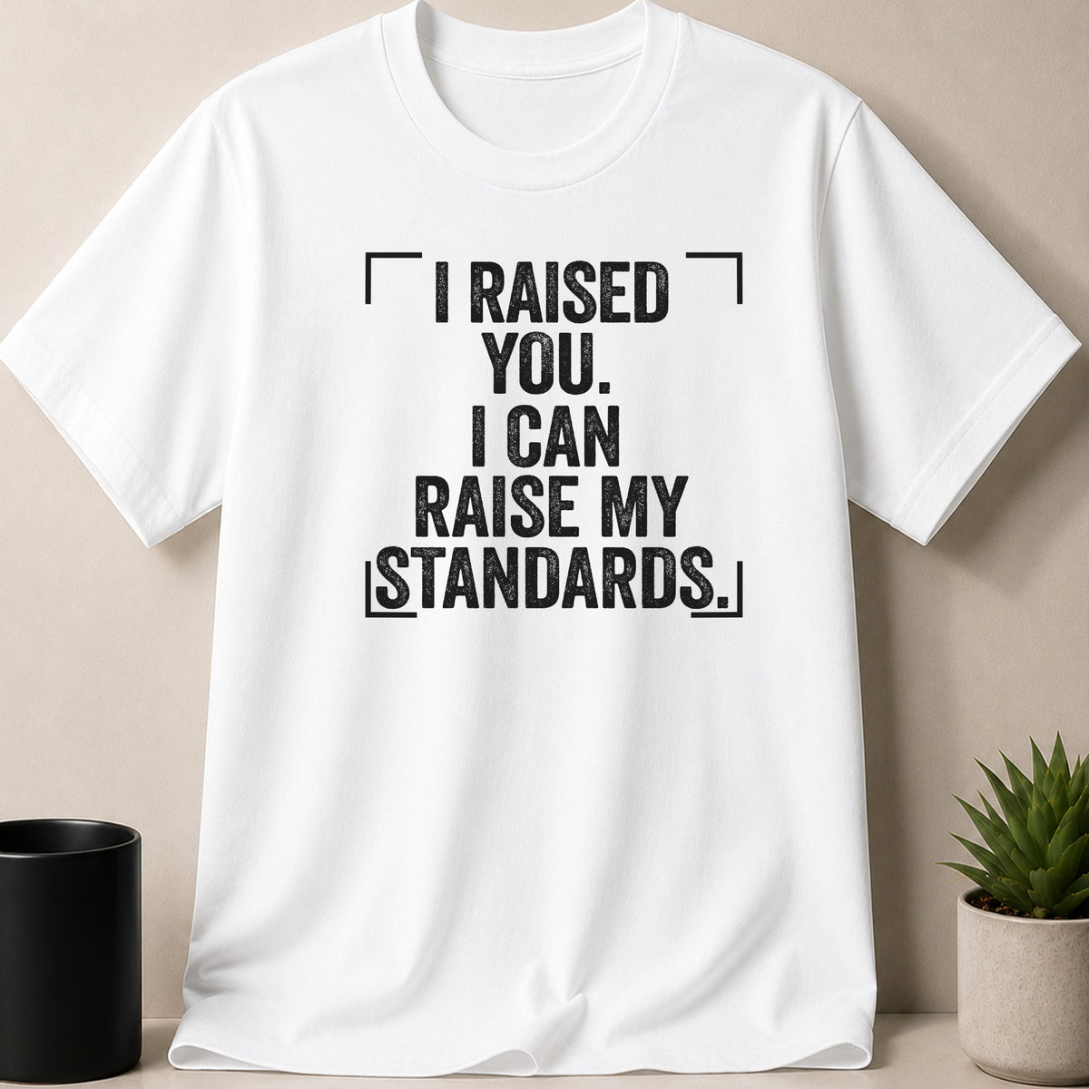 White t-shirt with black distressed text: "I RAISED YOU. I CAN RAISE MY STANDARDS."