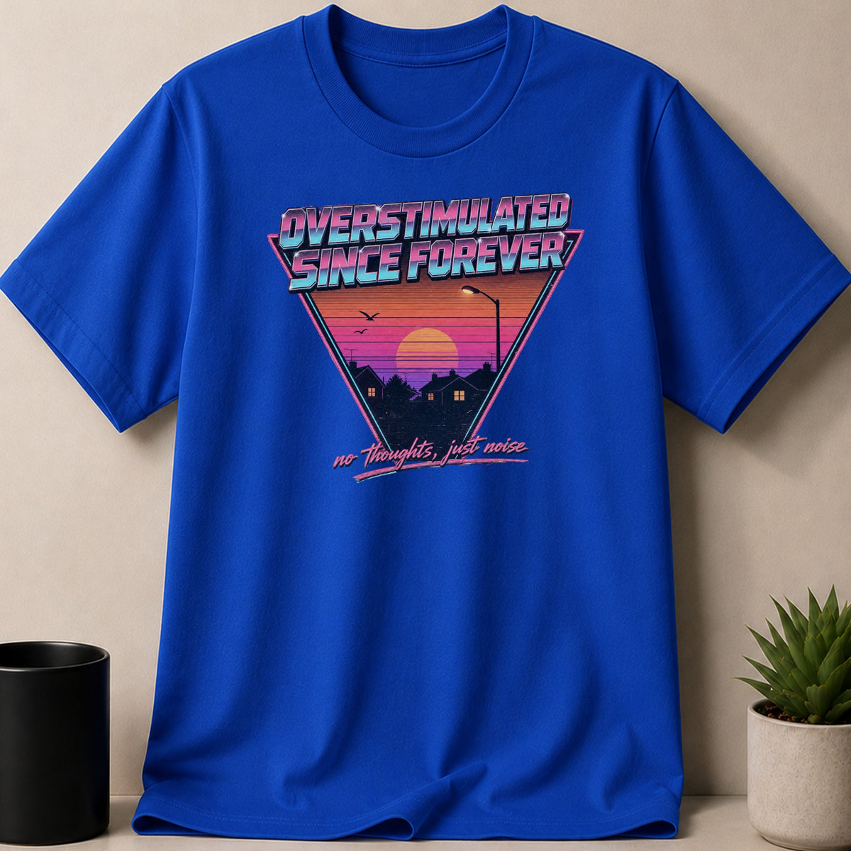 Blue t-shirt with retro graphic: "OVERSTIMULATED SINCE FOREVER" and "no thoughts, just noise."