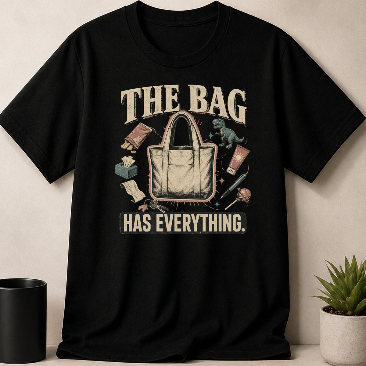 Black t-shirt with graphic "THE BAG HAS EVERYTHING." and illustrated items.